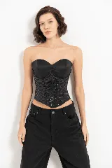 Corset negro con copas preformadas, ballenas y cierre trasero con ganchos. El cuerpo del corset está confeccionado en tejido con lentejuelas dispuestas en forma de chevron.
