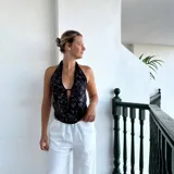 Top halter negro con estampado floral blanco y abertura en el centro del pecho.