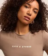 Remera color tostado de algodón y elastano, corte ajustado, cuello redondo y mangas cortas. Estampa frontal con la frase "Cute & Stress" en letras blancas.