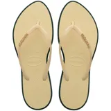 Ojotas Havaianas Slim Point color crema con contorno verde oscuro y logo en las tiras.