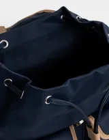 Mochila azul marino con detalles en cuero sintético color camel. Tiene solapa superior con cierre de hebilla, doble bolsillo frontal con hebilla, correa de ajuste y manija superior.