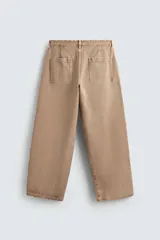 Pantalón de jean color beige, de corte ancho y tiro medio, con cinco bolsillos, efecto lavado y cierre frontal con cremallera y botón.