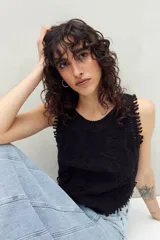 Musculosa negra con diseño bordado en relieve, calce recto y ruedo en pico. Detalles festoneados en sisas y escote.