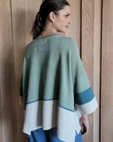 Buzo de punto con diseño de bloques de color negro, gris y beige. Tiene cuello redondo y mangas anchas tres cuartos.