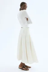Pollera midi color crema, de tiro alto, con tablas y silueta evasé.