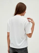 Remera negra de corte holgado con cuello en V y apliques de tachas doradas en los hombros.