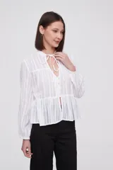Blusa blanca con rayas verticales, cuello con lazo, mangas largas y corte holgado.