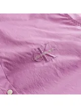 Camisa lila de corte relajado, con cuello clásico, cierre frontal con botones y logo de Calvin Klein Jeans bordado en el pecho.