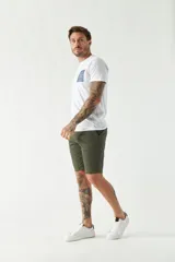 Bermuda color beige, de corte chino clásico, con bolsillos laterales y traseros, cierre con botón y cremallera, presillas para cinturón y logo bordado. Confeccionada en algodón y spandex.