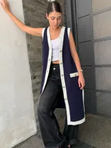 Vestido tipo chaleco azul marino con ribetes blancos, cuello en V, botones dorados y bolsillos frontales.