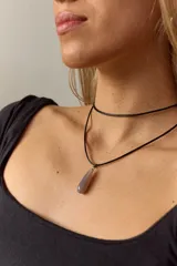 Gargantilla doble con choker de cuero negro y collar con dije de piedra natural marrón en forma de gota con engarce de acero quirúrgico hipoalergénico y tiento negro.