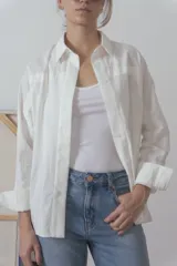 Camisa blanca de manga larga con cuello clásico y cierre frontal con botones.