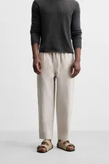 Pantalón de lino color marrón oscuro, de corte recto y relaxed fit. Tiene cintura elástica ajustable con cordón, bolsillos frontales y traseros de parche.