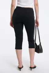 Calzas capri negras con cintura elástica y una raya blanca vertical a lo largo de la pierna.