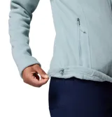 Polar de mujer Columbia, color azul claro, con cierre frontal completo, cuello alto y bolsillos laterales con cremallera. Presenta un bolsillo con cremallera en la manga izquierda y costuras horizontales a la altura del pecho.