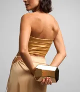 Blusa cropped color beige de satén con escote strapless, diseño con pliegues horizontales y cierre lateral con cremallera invisible.