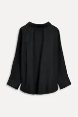 Camisa negra de algodón con cuello solapa, manga larga tipo murciélago con puños abotonados, hombros caídos, bolsillo de parche en el pecho, pinzas en la espalda y cierre frontal con botones.