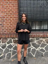 Camisa blanca de mangas largas con detalles de encaje en el cuello y el pecho.