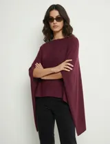 Poncho tejido de punto grueso, color mostaza/mostaza oscuro, con cuello redondo y caída amplia.