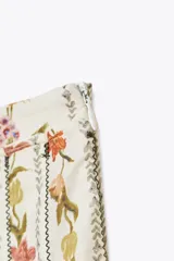 Falda midi de tiro medio confeccionada en hilatura de algodón. Tejido con tablas y estampado floral. Bajo acabado en vivo a contraste. Cierre lateral con cremallera oculta en costura.