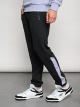 Pantalón de jogging negro con puños ajustados, cortes laterales y cambio de color en la parte inferior de la pierna.
