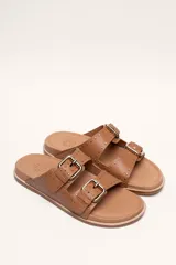 Sandalias marrones de cuero vacuno con doble tira y hebillas metálicas ajustables.