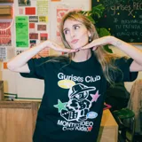 Remera negra de corte boxy con estampa de un personaje de historieta con gorra, dados y estrellas. Incluye texto "Gurises Club", "Uruguay", "Montevideo Cool Kids" y el logo de la marca Kaboa.