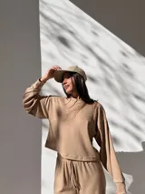 Conjunto deportivo color beige de tela waffle, compuesto por un buzo de corte cropped y un pantalón con cordón ajustable.