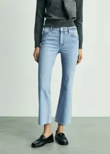 Jeans de tiro alto color celeste, corte flare, con cierre de cremallera y botón, cinco bolsillos, bajo deshilachado y tejido elástico.