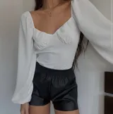 Body blanco con escote corazón, mangas largas abullonadas y espalda abierta con tiras para atar.