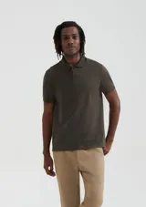 Polo verde oscuro de manga corta, confeccionada en algodón pima, con cuello clásico y tapeta de dos botones.