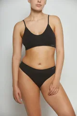 Top deportivo negro sin costuras, con breteles finos y logo pequeño en el lateral.