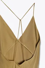 Vestido largo marrón de Zara Woman Collection, confeccionado en viscosa y lyocell. Presenta escote en pico y tirantes finos cruzados en la espalda.