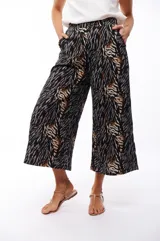 Pantalón capri negro con estampado abstracto en tonos beige, gris y marrón.