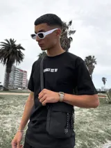 Bandolera negra con correa ajustable y cinco bolsillos.