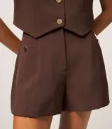 Short de sastre color marrón, de cintura alta, con bolsillos laterales decorados con tachuelas metalizadas y recortes delanteros.