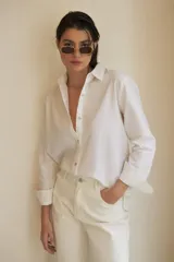 Camisa blanca de corte clásico, con cuello camisero, mangas largas con puños abotonados y cierre frontal con botones.