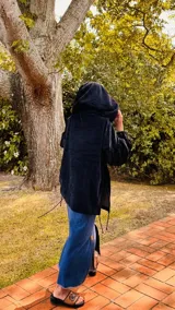 Buzo tipo canguro oversize de tela plush, color azul claro. Presenta capucha, cierre frontal parcial con cordón turquesa y bolsillos canguro frontales. Las mangas son largas y abullonadas con puños ajustados.