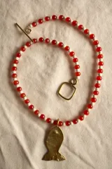 Collar con cuentas rojas y medallones de bronce en forma de pez.