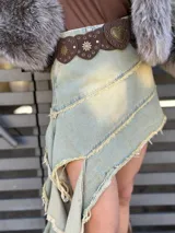 Minifalda de denim verde con detalles de desteñido amarillo y ruedo irregular con flecos.