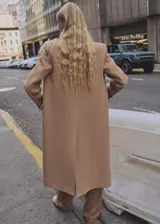 Abrigo largo color camel, con cuello de solapa, doble botonadura y bolsillos laterales con solapa. Confeccionado en mezcla de lana con forro interior.