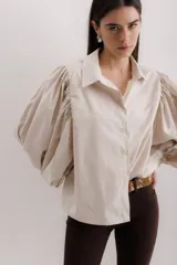 Camisa color beige de algodón con mangas abullonadas y cierre con botones.