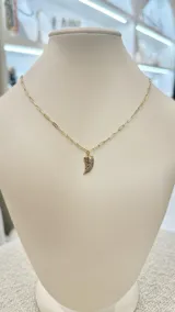 Collar con cadena dorada de eslabones alargados y dije en forma de cuerno con incrustaciones de piedras negras.