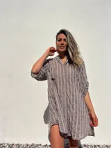 Camisero corto color habano con bordado de líneas verticales blancas. Tiene cuello camisero, mangas cortas y cierre frontal con botones.