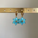 Aros de cobre enchapados en oro de 18k, con diseño de flor en color celeste e incrustaciones de circonia.
