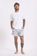 Short de baño con estampado de flores de loto y hojas en tonos amarillo, naranja y verde sobre fondo azul.