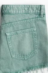 Short de jean color verde agua, de tiro medio, con cinco bolsillos y terminaciones desflecadas.