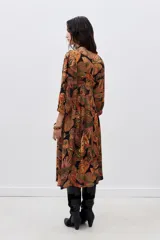 Vestido midi con estampado de mariposas en tonos naranja, verde y negro. Tiene escote en V, mangas largas abullonadas y abertura lateral en la falda.