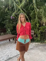 Camisa corta color rojo con escote en V y mangas largas acampanadas. Presenta ajuste frontal con lazos.