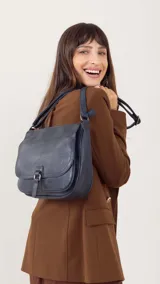 Bandolera azul de cuero sintético con tapa y broche, correa larga regulable, bolsillo principal y bolsillos internos organizadores.